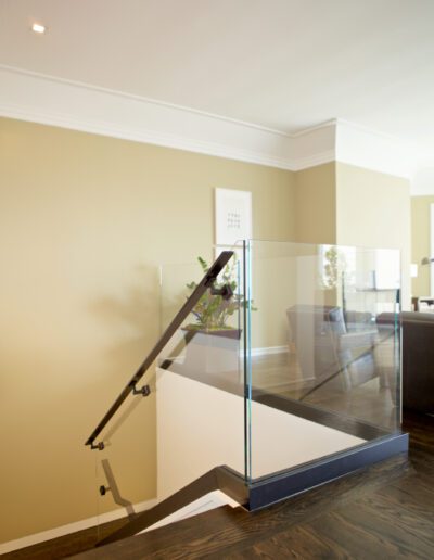 Modern staircase with glass railing and dark wood floor in a contemporary home interior.