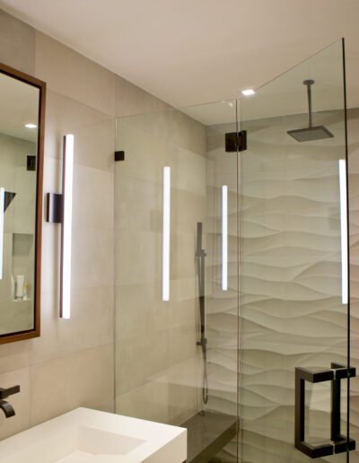 Modern bathroom with textured walls, a walk-in shower, and reflective mirror.