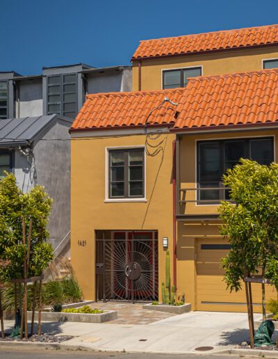 Three urban houses showcasing different architectural styles and colors with blue sky in the background.