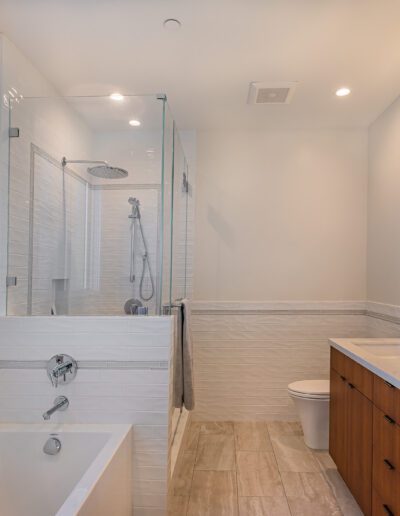 Modern bathroom with a glass-enclosed shower, dual sink vanity, and a bathtub.