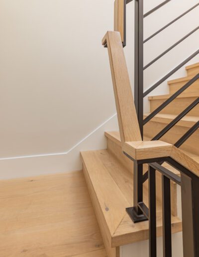 Modern wooden staircase with metal balusters and led lighting trim.