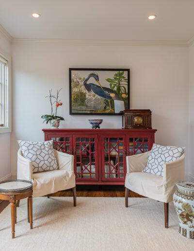 Elegantly decorated room with a traditional red cabinet, two white armchairs, and asian-inspired decorative elements.