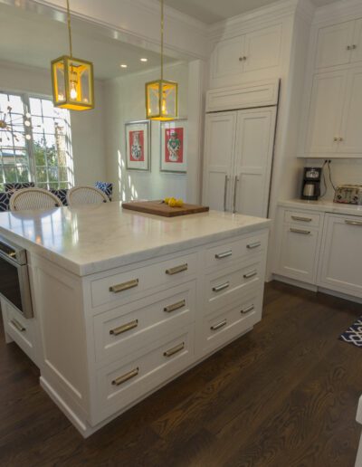 Modern kitchen interior with white cabinetry, marble countertops, and pendant lighting.