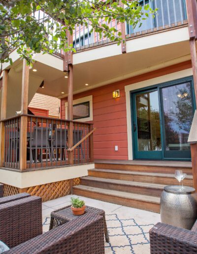 Comfortable outdoor seating area in front of a modern house with a red facade and a small, inviting porch.