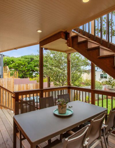 Spacious wooden deck with outdoor seating and staircase leading to the yard.